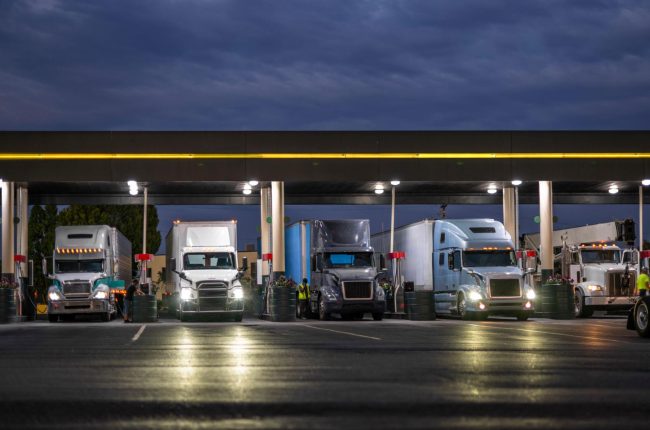 A semi truck fueling alone at a truck stop at night, symbolizing the financial pressure and fuel volatility facing trucking companies in today’s freight market.